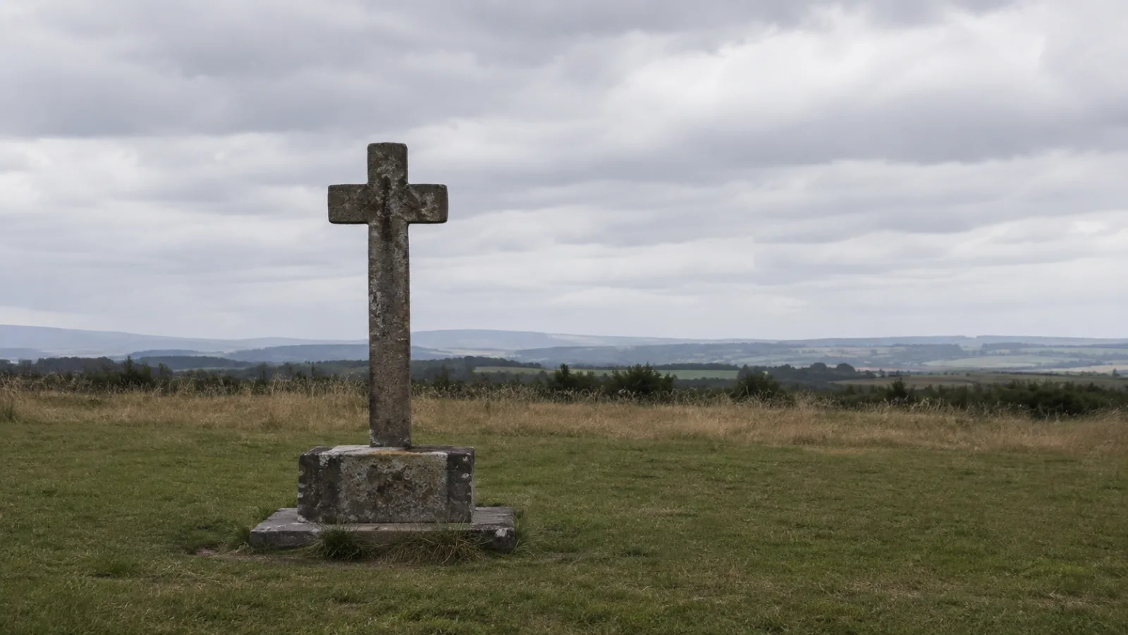 A present-day stone memorial cross standing alone in an open field where the Hinterkaifeck farmhouse once stood