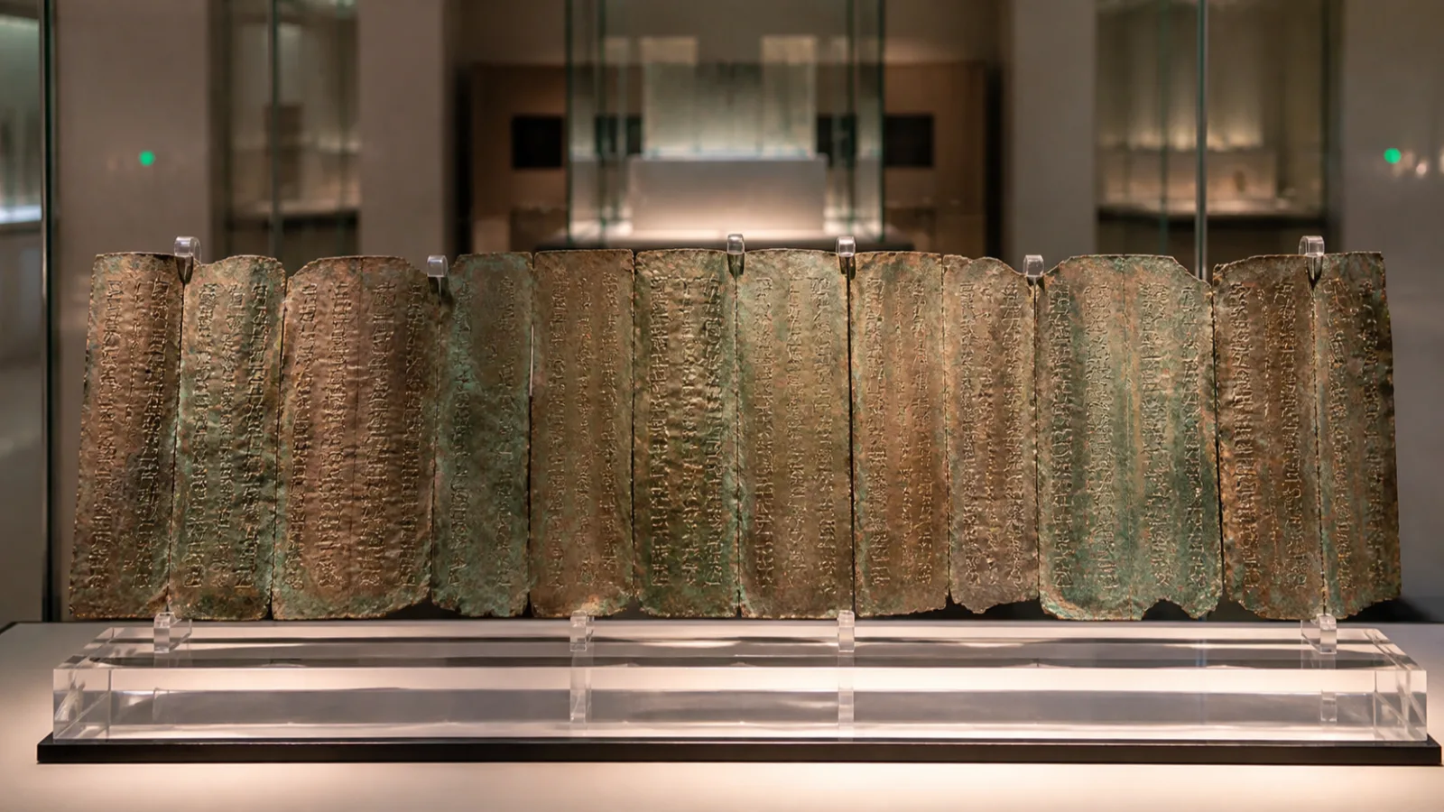 Modern museum display case showing reassembled ancient copper scroll strips